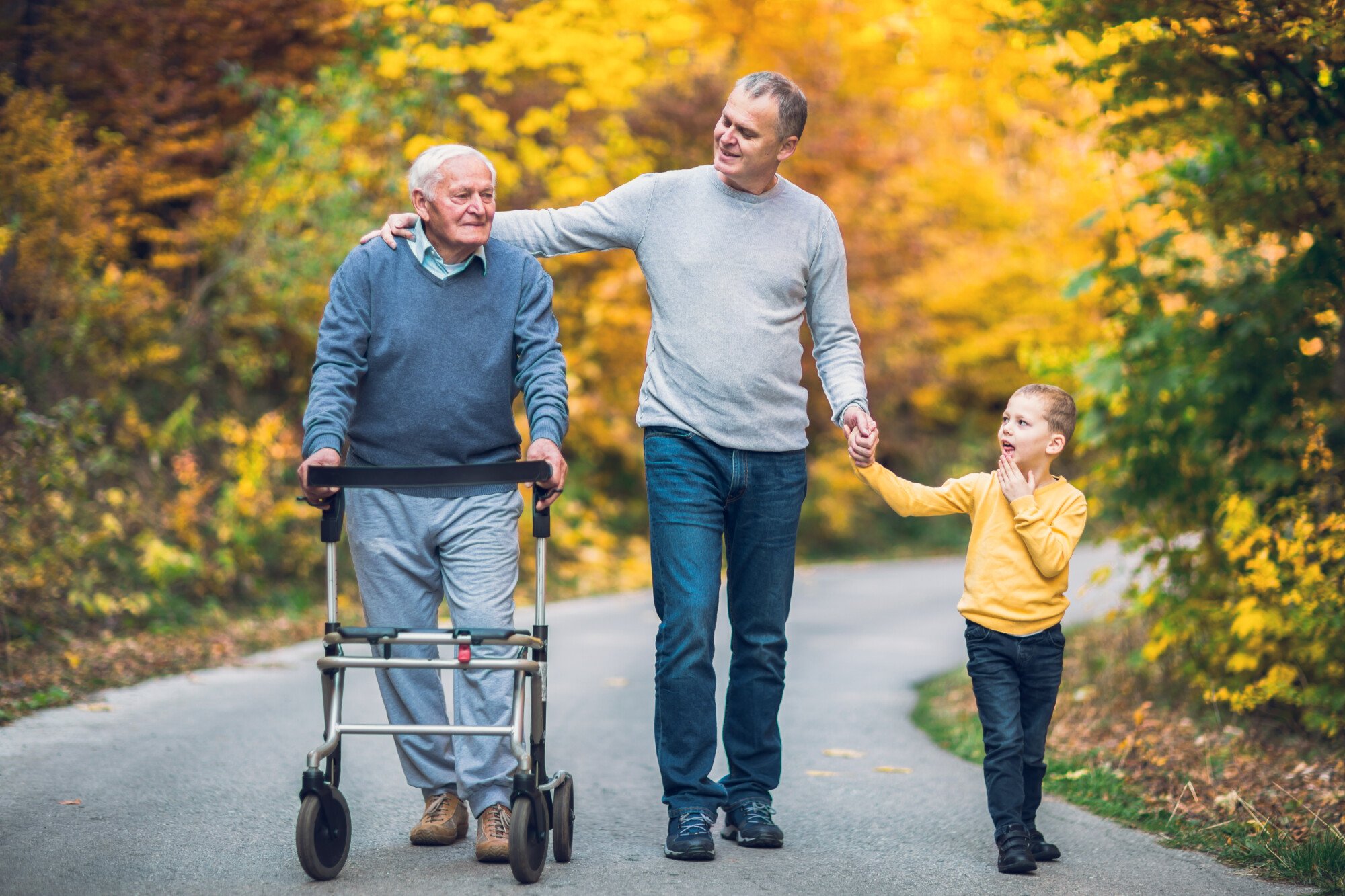 Male caretaker walking with little boy and elderly man